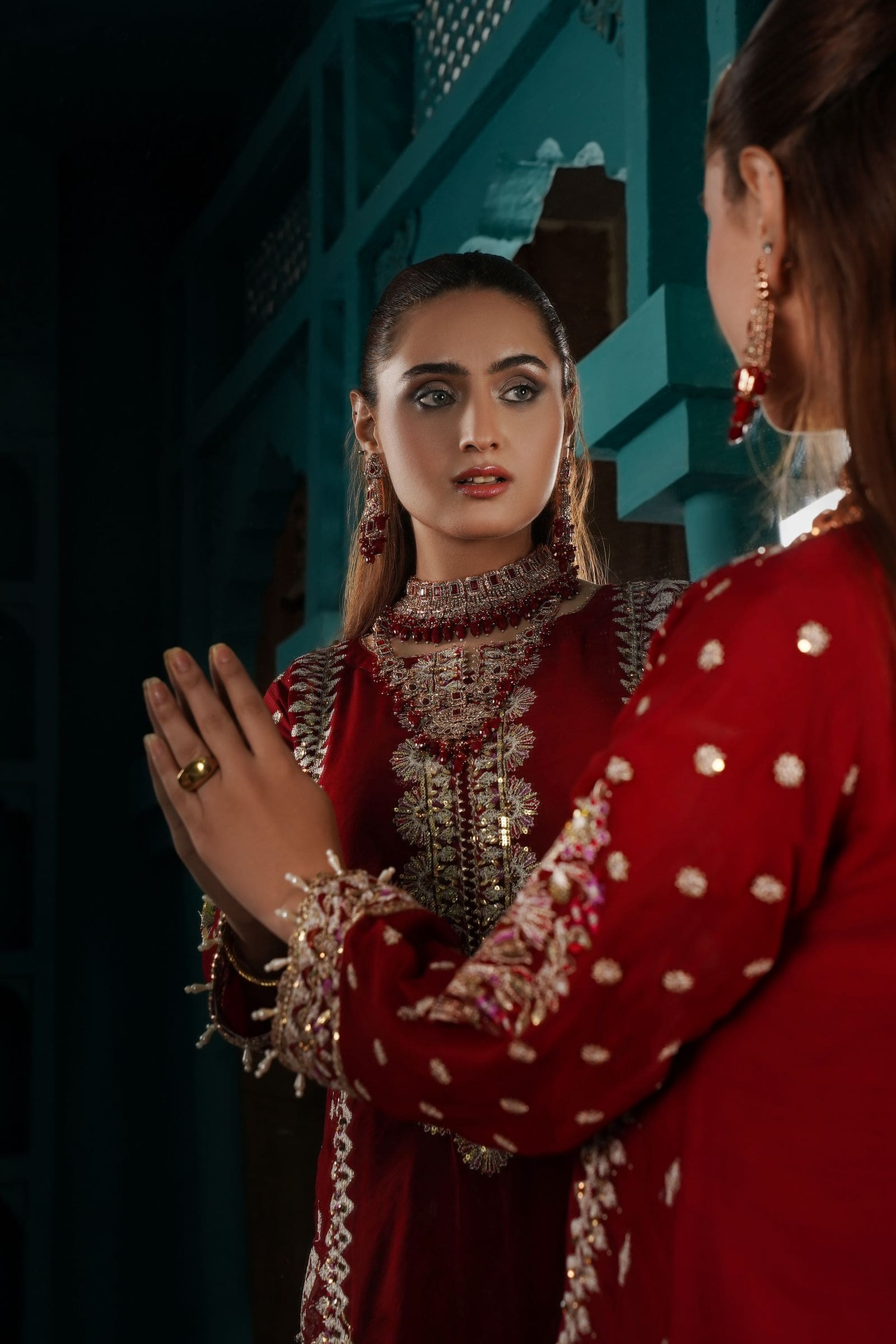 عارضة بفستان أحمر مطرّز على خلفية داكنة